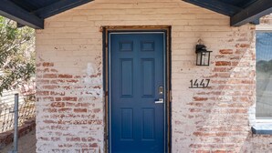 A blue door with the number 1447 on a brick wall, under a dark roof.