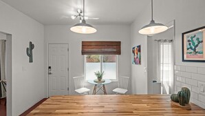 A dining area with a wooden table, two pendant lights, and a window with a view.