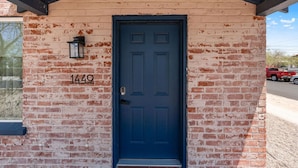 A brick building with a dark blue door and a small window.