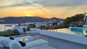 A rooftop pool area with a view of a coastal town at sunset. - My Rental Homes - Villa Waves with pool and Jacuzzi. Close to Platis Gialos beach (Mykonos)