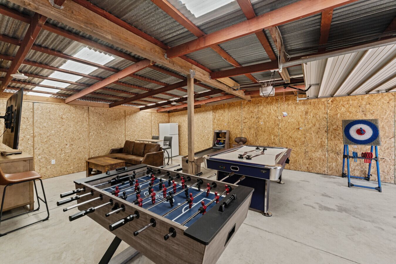 An indoor recreational area with a foosball table, a dartboard, and a ping pong table.