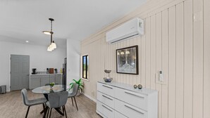 Una cocina moderna con comedor, que cuenta con un armario blanco, una lámpara colgante y un ventanal con vistas.
