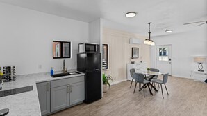 Una cocina moderna con armarios grises, un refrigerador negro, un microondas y un comedor con mesa y sillas.