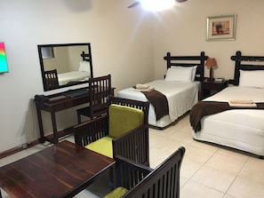 A hotel room with two beds, a desk with a telephone, a chair, and a mirror. - Zaks Place Hotel (Bulawayo)