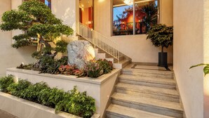 A staircase with a stone balustrade, surrounded by a variety of plants and a bonsai tree. - Amber Bay Hotel & Suites Da Nang (Da Nang)
