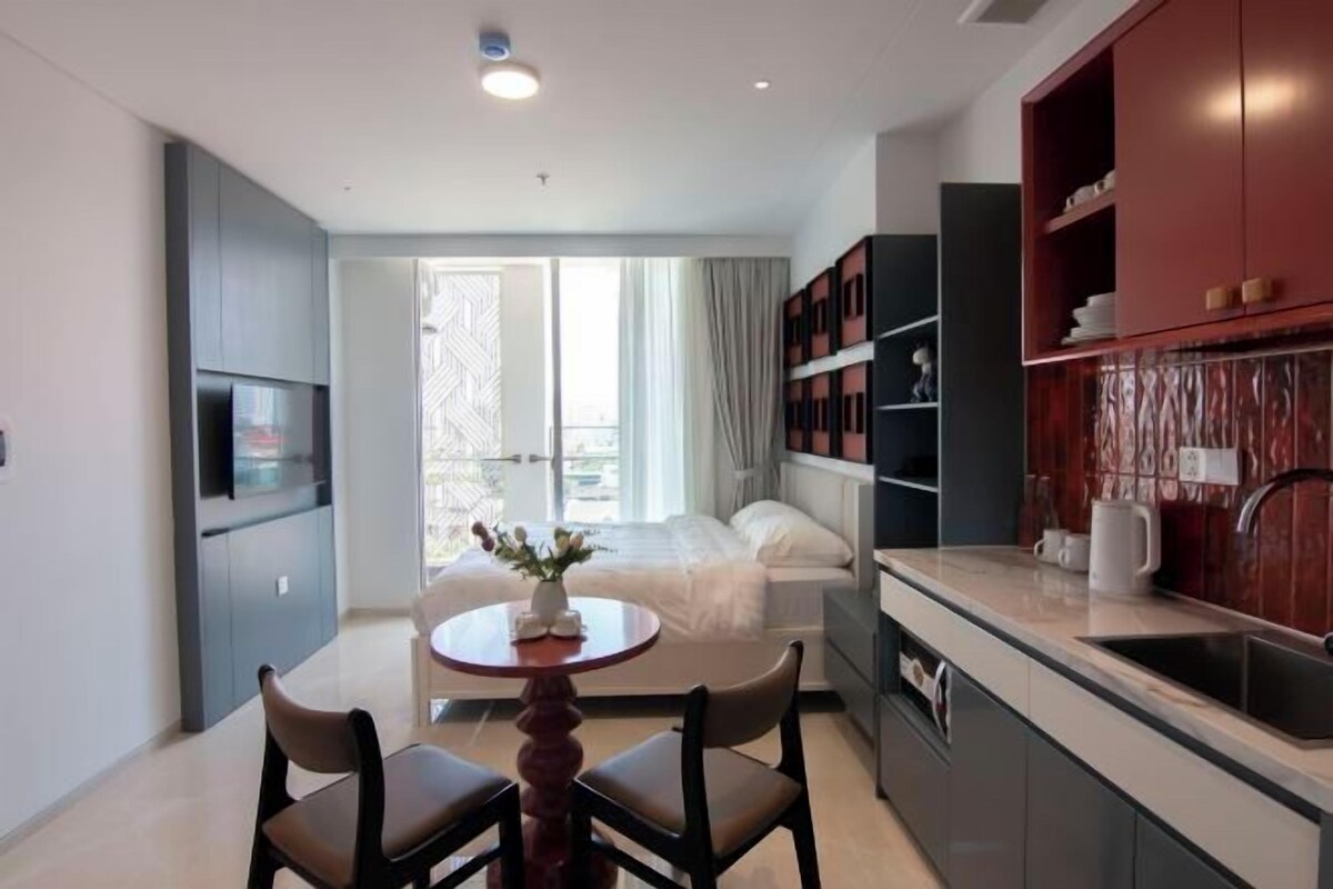 A modern kitchen with grey cabinets, a dining area with a round table and chairs, and a large window with curtains.