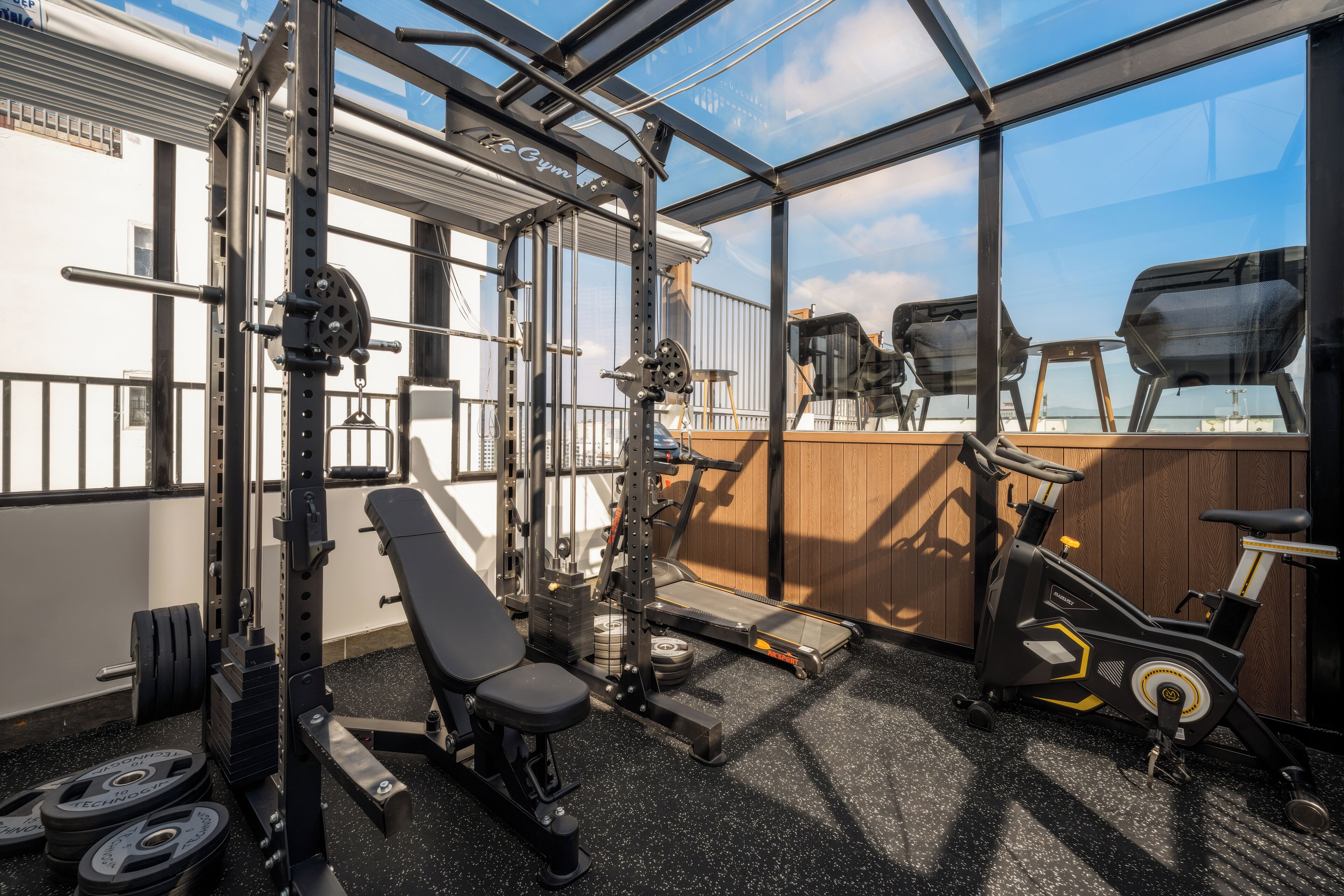Un gimnasio con cinta de correr, banco de pesas y diversos equipos de ejercicio.