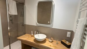 A modern bathroom with a wooden vanity, a large mirror, a built-in sink, and a shower area. - Les Chambres d'Hôtes du Château Eclosion (Saint-Paul en Jarez)