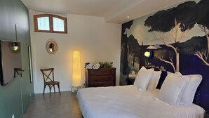 A bedroom with a bed, a dresser, a chair, a floor lamp, and a wall mural. - Les Chambres d'Hôtes du Château Eclosion (Saint-Paul en Jarez)