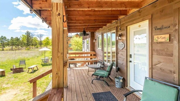 A wooden porch with outdoor seating, a welcome sign, and a sign reading "Rivershow."