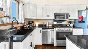 A modern kitchen with white cabinets, stainless steel appliances, and a black countertop.