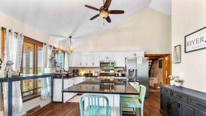 A modern kitchen with white cabinets, a central island, and a ceiling fan.