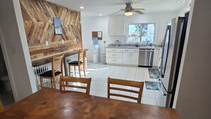 A dining area with a wooden table and chairs, a herringbone-patterned wall, and a kitchen in the background. - Spacious 5-bedroom beautiful water view home with private boat dock! (Homosassa)