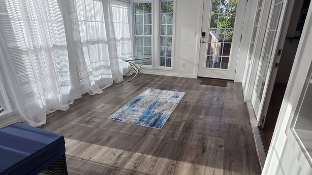 A spacious room with wooden flooring, a glass table, and a blue rug. - Spacious 5-bedroom beautiful water view home with private boat dock! (Homosassa)