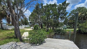 A wooden dock extending into a body of water, surrounded by trees and a grassy area. - Spacious 5-bedroom beautiful water view home with private boat dock! (Homosassa)