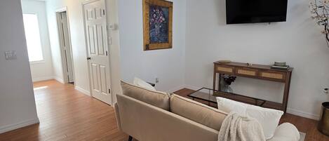Una sala de estar con ventilador de techo, televisor de pantalla plana, sofá y una mesa de centro de madera.