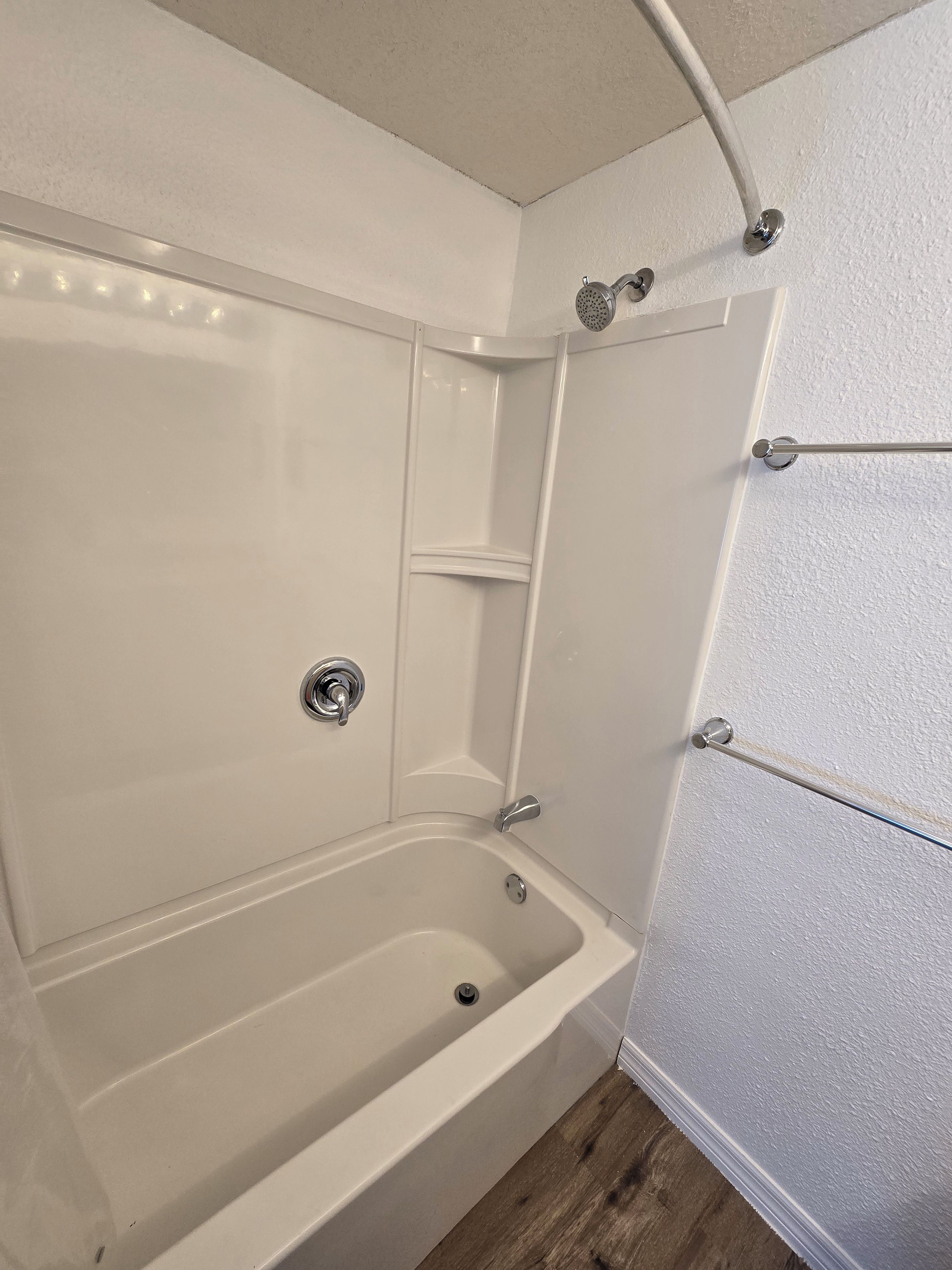 Ein Badezimmer im Eck mit Badewanne, Dusche und Toilette.