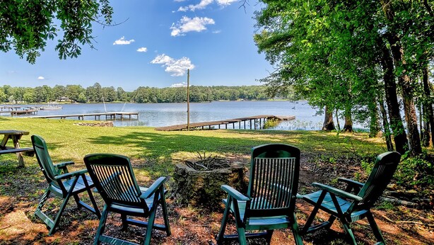 Vista de un lago con barcos amarrados, sillas verdes y una mesa de picnic.