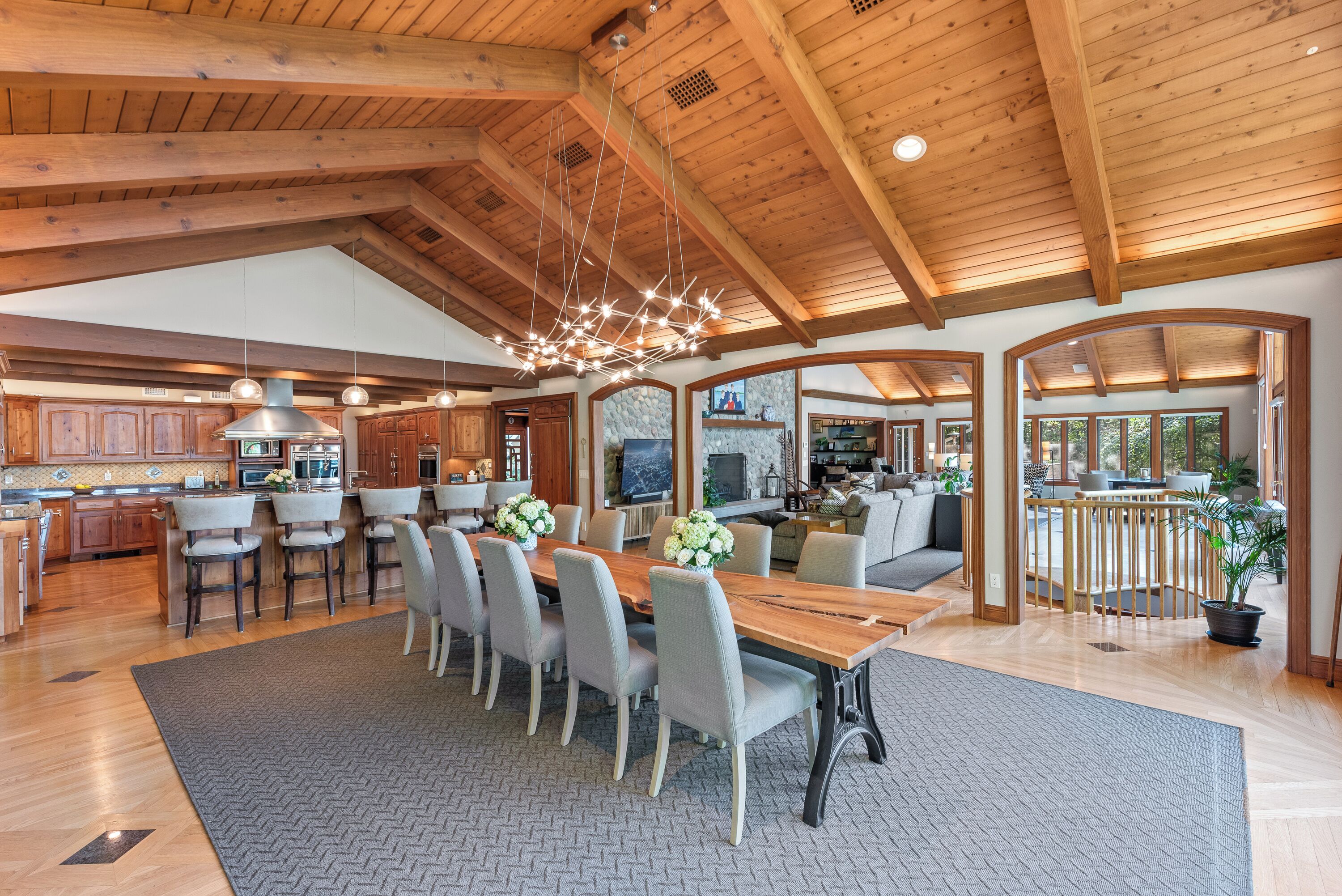 A spacious kitchen with wooden beams, a dining area with a long table and chairs, and a view of the living area.