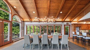A dining area with a wooden ceiling, large windows, and a chandelier. - Kohl Manor Luxury Lake 8br year round retreat Pool, Cinema, Arcade on LacLaBelle (Oconomowoc)