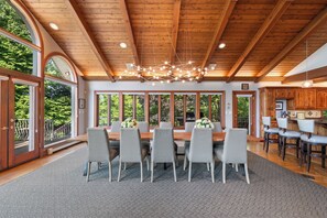 A dining area with a wooden ceiling, large windows, and a chandelier.