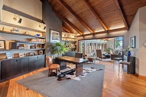 A spacious living area with a wooden ceiling, a dining table, and a large rug.