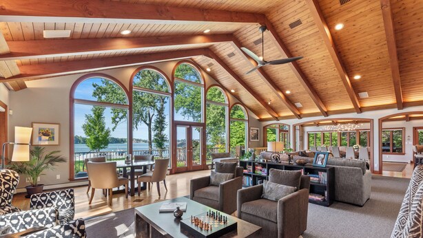 A spacious living area with a high ceiling, large windows, and a view of the outdoors. - Kohl Manor Luxury Lake 8br year round retreat Pool, Cinema, Arcade on LacLaBelle (Oconomowoc)