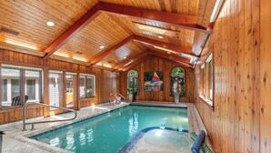 An indoor swimming pool with wooden walls and a sloped ceiling. - Kohl Manor Luxury Lake 8br year round retreat Pool, Cinema, Arcade on LacLaBelle (Oconomowoc)