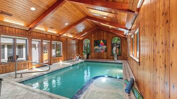 Une piscine intérieure avec des murs en bois et un plafond incliné.