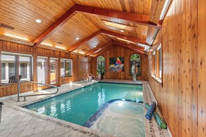 An indoor swimming pool with wooden walls and a sloped ceiling.