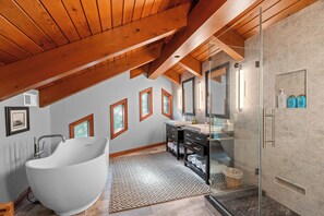 A modern bathroom with a freestanding bathtub, a glass-enclosed shower, and a vanity with a mirror.