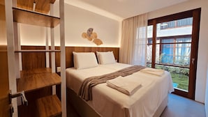 Une chambre d’hôtel avec un lit, une étagère en bois, un luminaire au plafond et une fenêtre avec des rideaux.