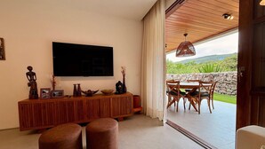 Un salon moderne avec un téléviseur à écran plat, une console en bois et des poufs.