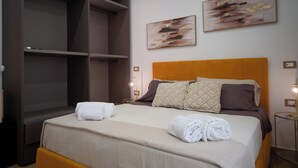 Hotellihuone, jossa on sänky, vaatekaappi ja kaksi abstraktia maalausta seinällä.
