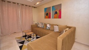 A living room with a beige sofa, a small table, and colorful abstract art on the wall.