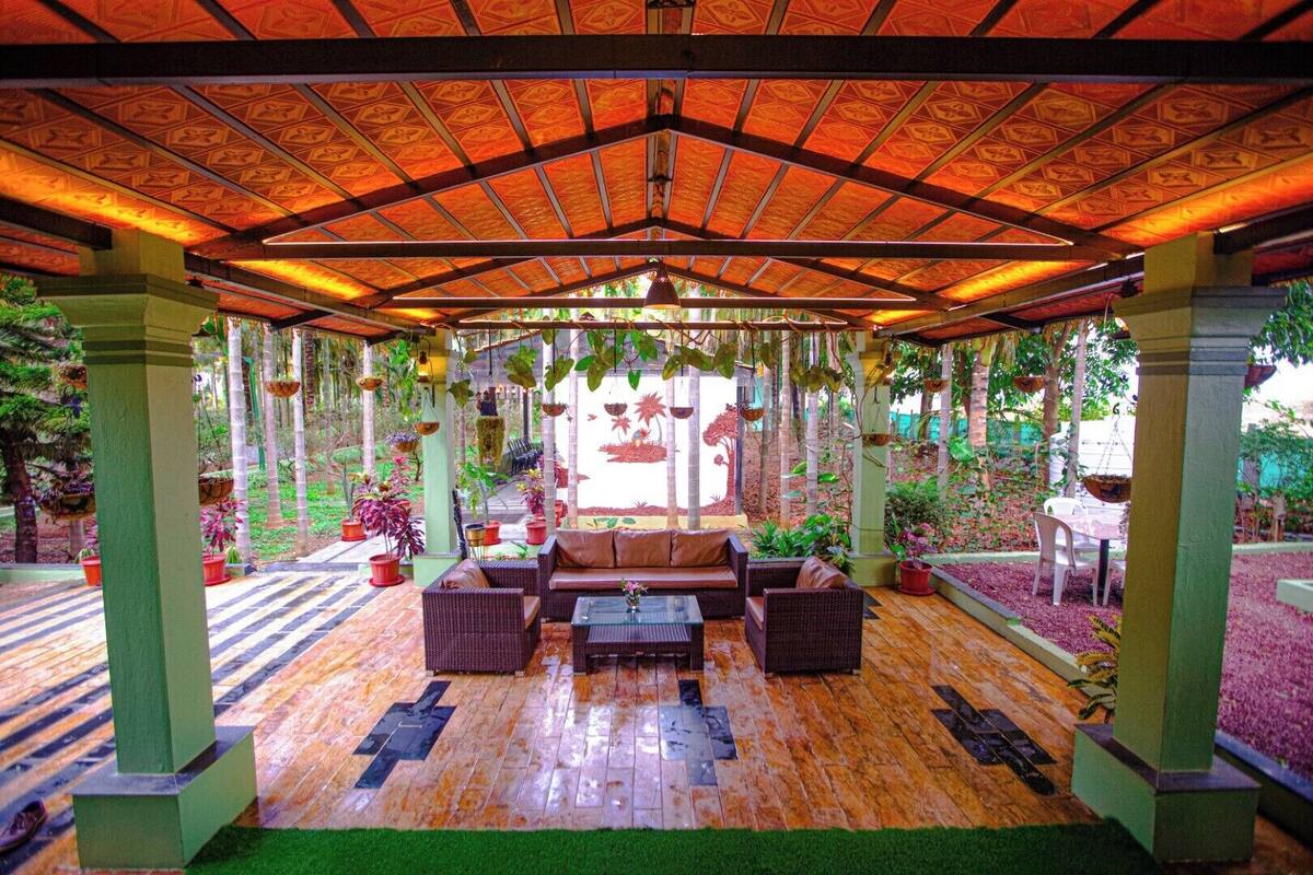 An indoor garden with a wooden floor, green pillars, and hanging plants.