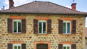 A stone building with six windows, each with shutters.