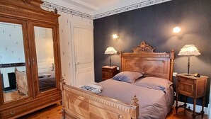 A bedroom with a wooden bed, two bedside tables with lamps, a large mirror, and a dark accent wall.