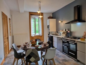 A modern kitchen with a dining area, featuring a stove, oven, and a dining table with chairs.