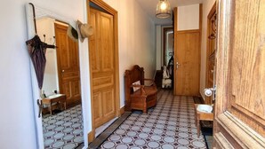 A hallway with patterned flooring, wooden doors, a mirror, and a hanging hat.