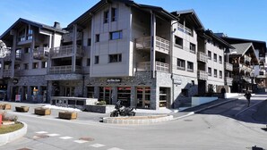 A multi-story hotel with balconies, a stone facade, and a ski resort sign. - Chic apartment in Les Gets center, sleeps 6, near ski and shops (Les Gets)