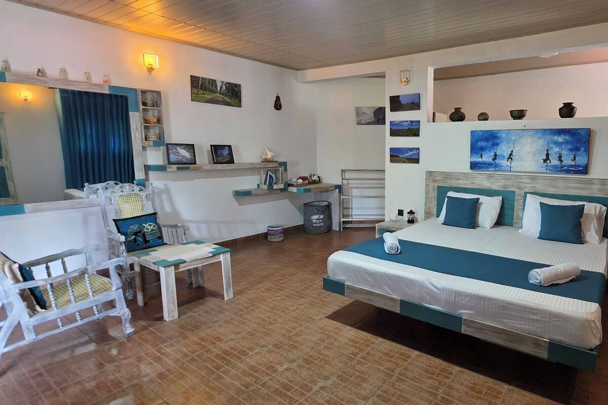 A bedroom with a bed, a chair, a desk, and a large mirror.