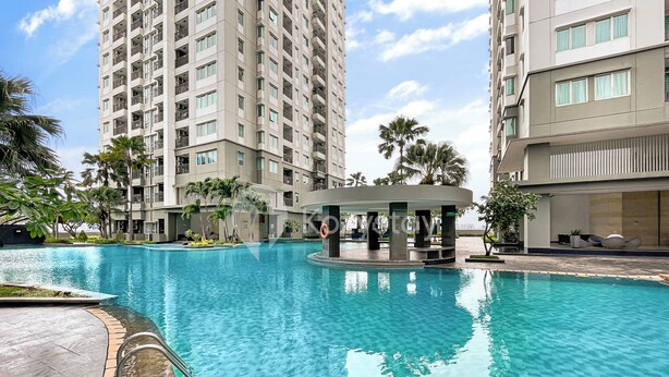 A swimming pool surrounded by high-rise buildings with balconies, a covered seating area, and palm trees. - Minoa by Kozystay - Thamrin (Jakarta)