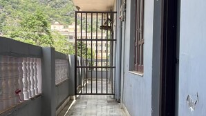 Un pasillo con suelo de baldosas, una reja metálica y un edificio de fachada azul.