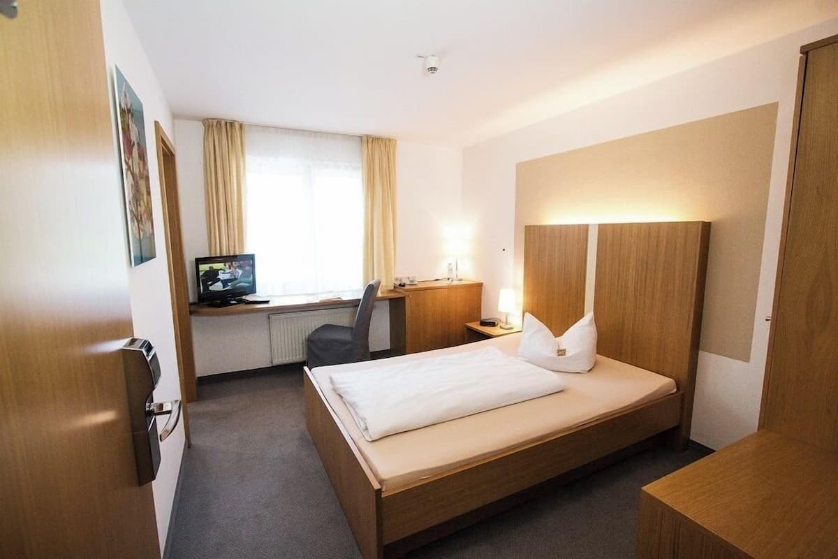 Une chambre d’hôtel équipée d’un lit, d’un bureau, d’une chaise, d’une télévision et d’une table de chevet avec une lampe.