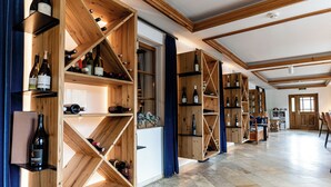 Una habitación amplia con estanterías de madera llenas de botellas de vino, un ventanal grande y suelo de baldosas.