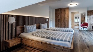 Un dormitorio moderno con cabecera de madera, una cama grande con ropa de cama a rayas, una mesita de noche y una silla roja en la esquina.