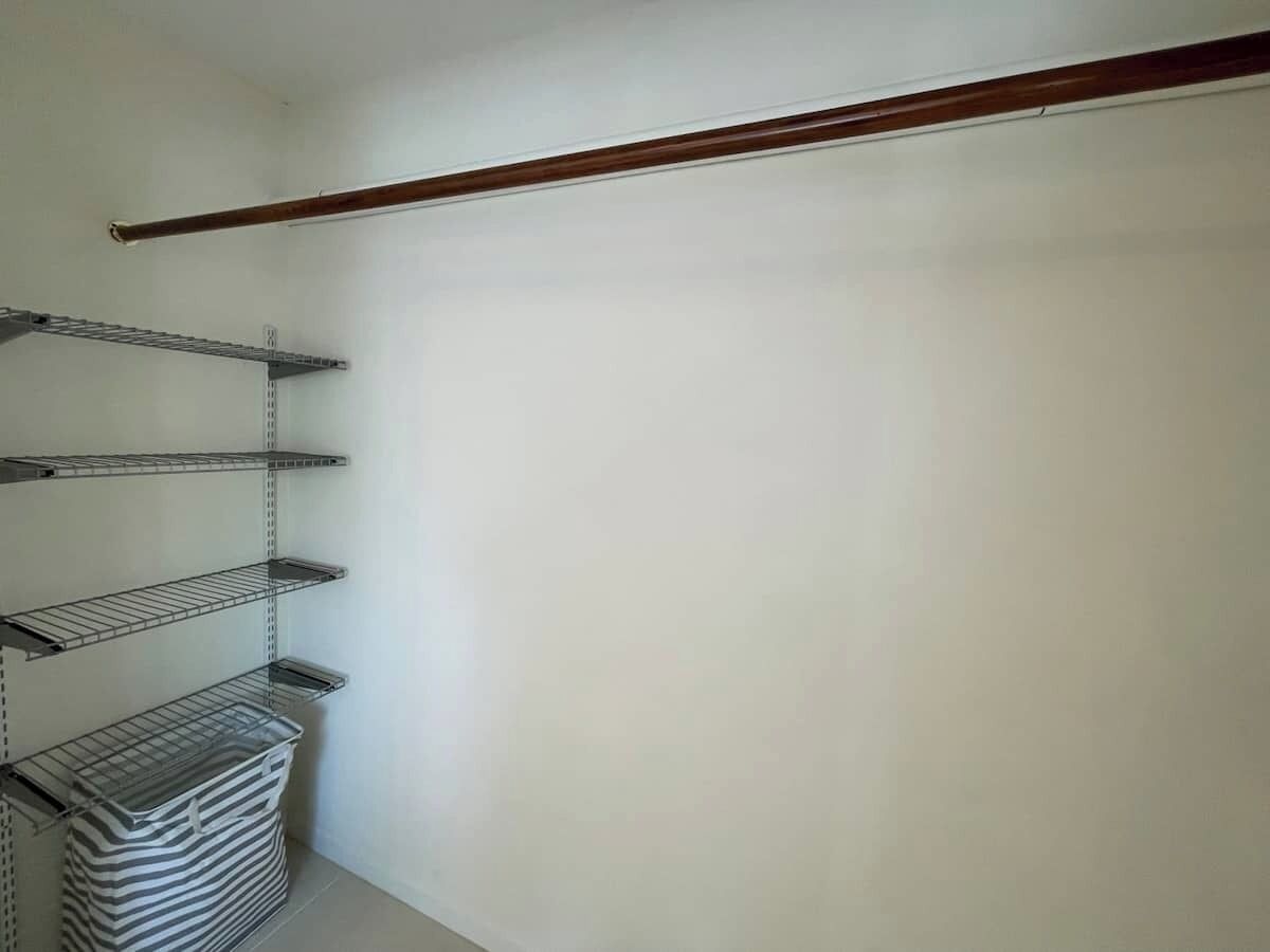 A storage closet with metal shelves and a wooden beam.