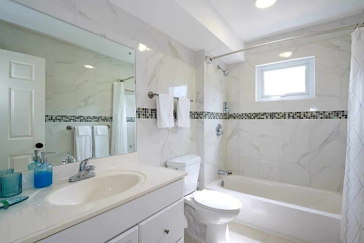 Une salle de bain avec un grand miroir, un lavabo, des toilettes et une baignoire.