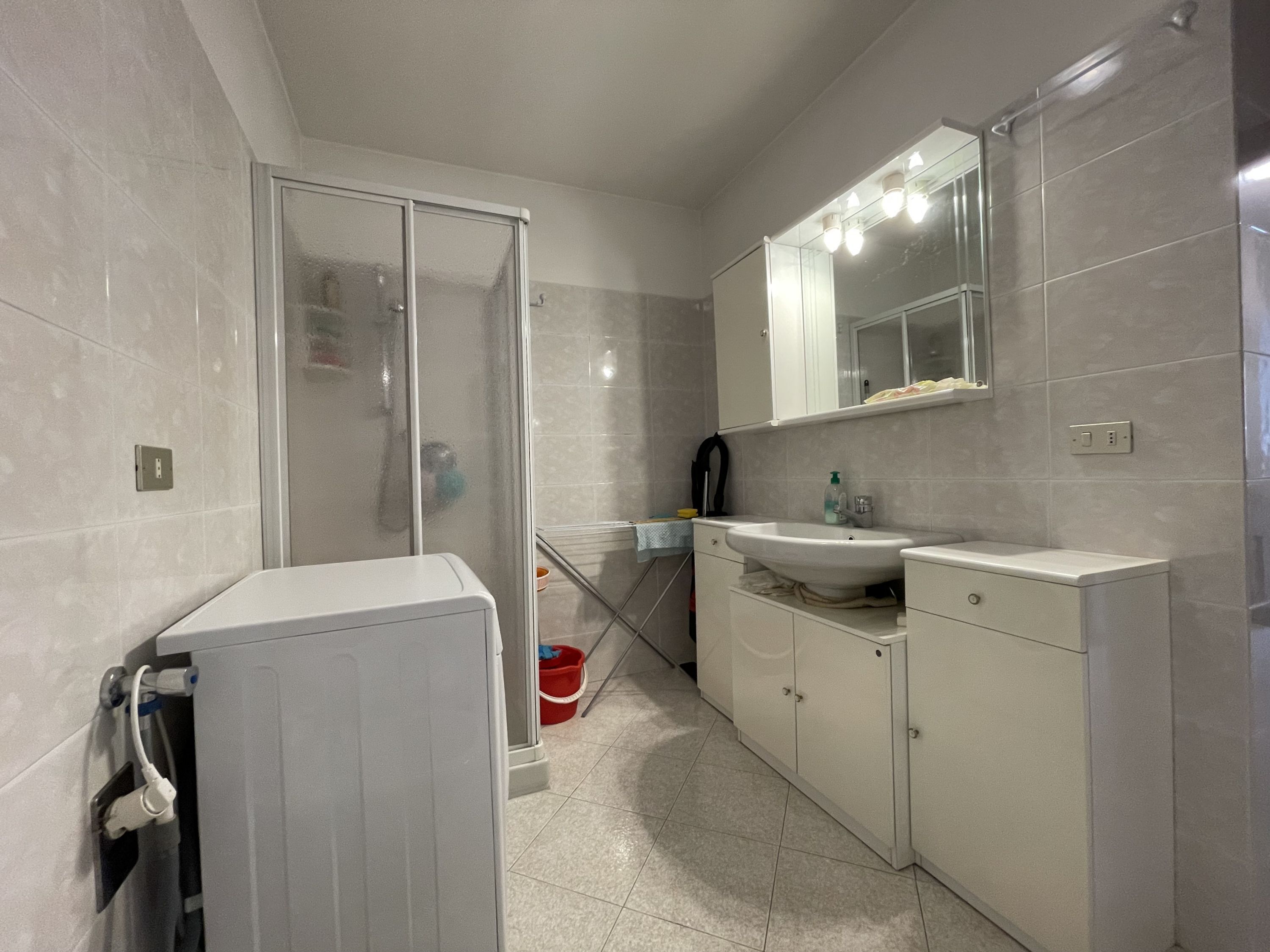 Une salle de bain moderne avec une douche à parois de verre, un lavabo blanc et un miroir au-dessus du lavabo.